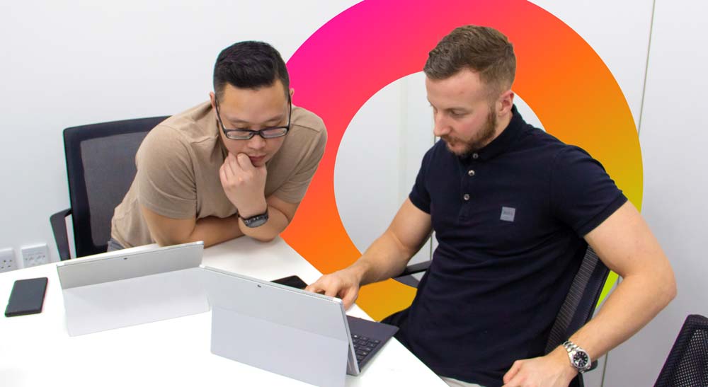 Two employees review information on a laptop