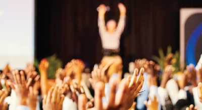 People raising hands in assemmbly