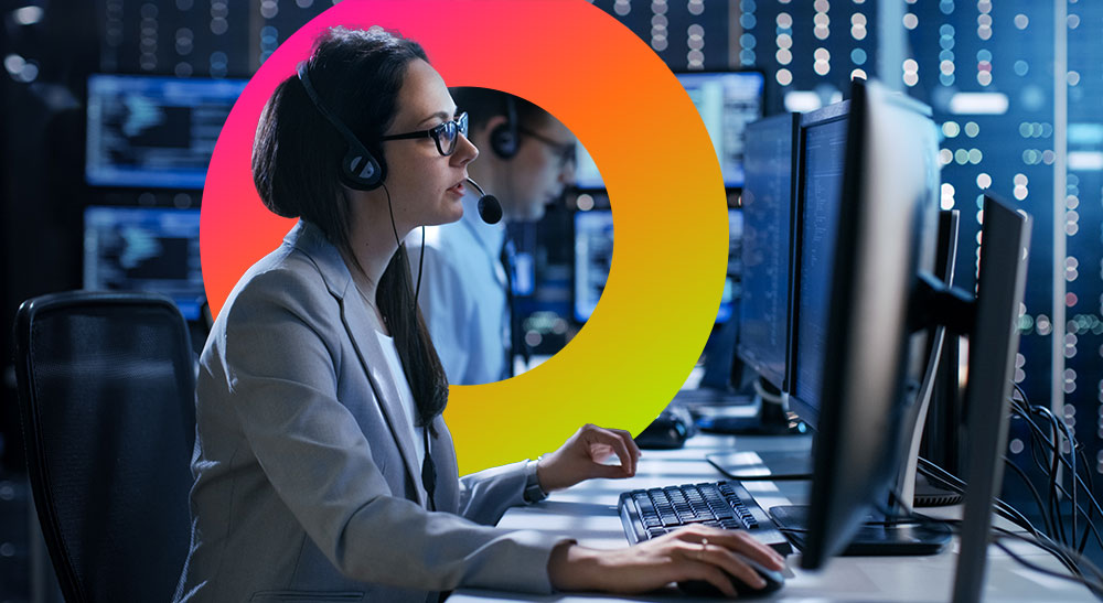 Woman with headset on taking a call working on computer monitors