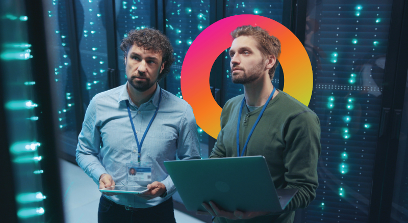 Two professionals examining data in a server room.