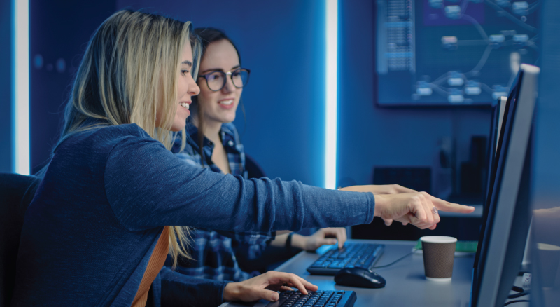 Two women programers working on a computer in data center