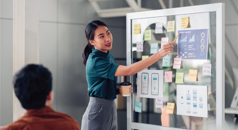 Woman ponting to board going over ideas