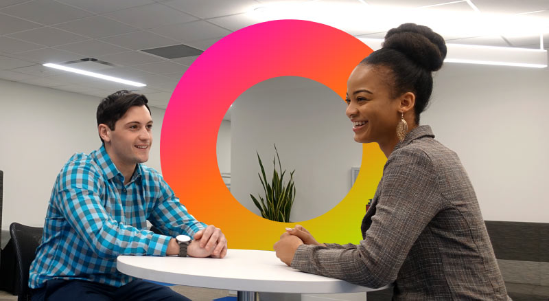 Two individuals sit at a table in an office