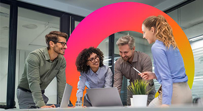 Coworkers huddle around a laptop while they interact with the screen