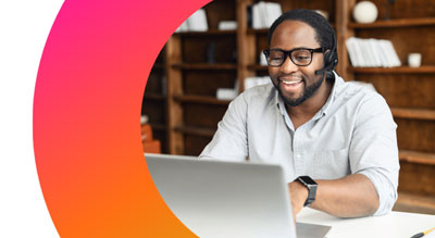 A smiling employee uses laptop while wearing a headset