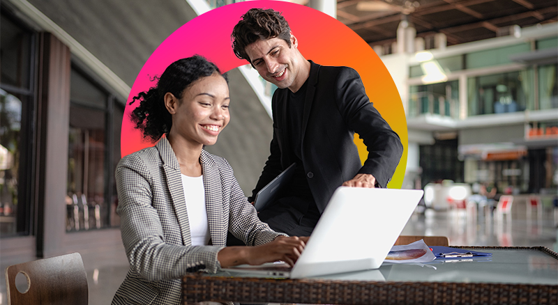 Two people in an office setting pointing at a laptop