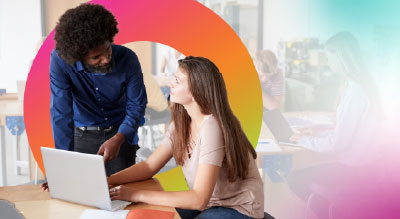 Two coworkers in a lively discussion behind a laptop