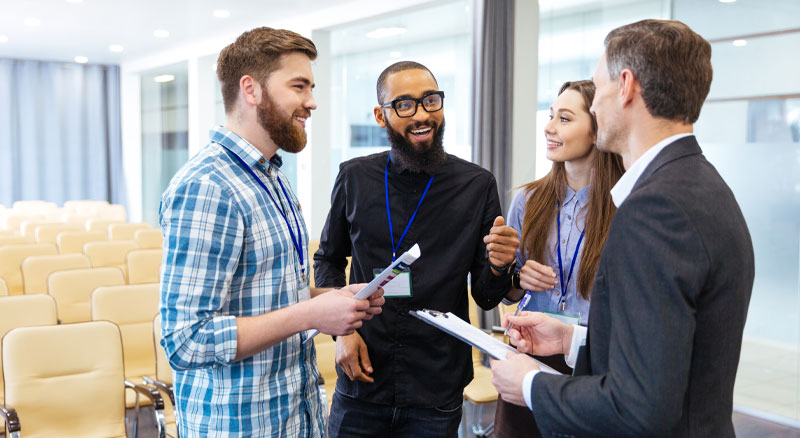 Four individuals hold a discussion during a conference