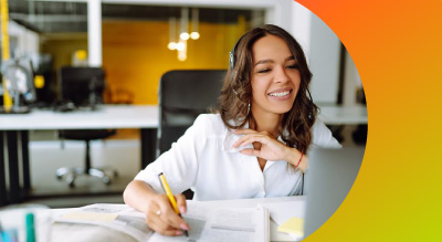 A woman smiling while focused on her laptop