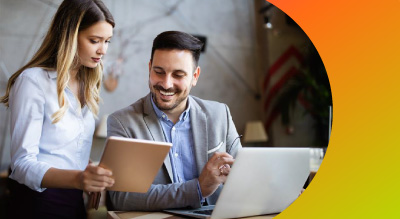 two smiling individuals looking at a tablet in a coworking environment