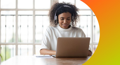 A girl seated at her computer wearing headphones