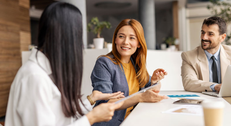 Three people discuss a contract in an office setting
