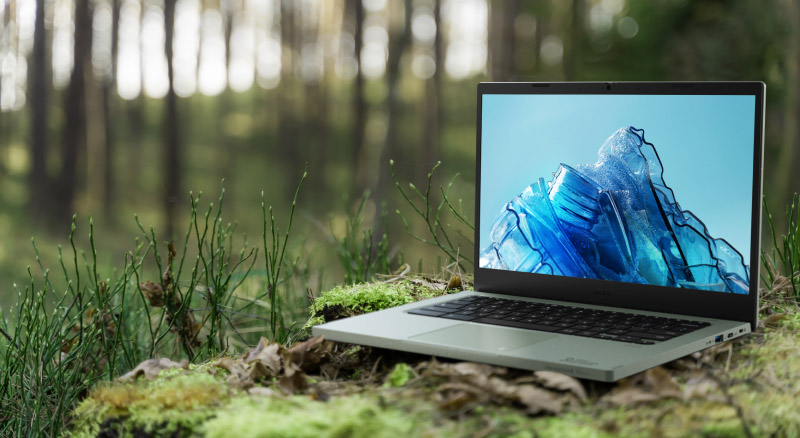 Chromebook vero laptop sitting on moss covered ground with trees behind it