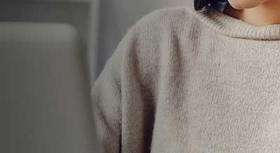 A person wearing a grey sweater using a laptop