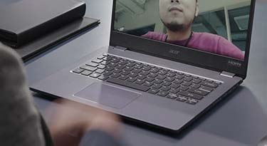 A person using an Acer laptop with another person in the screen