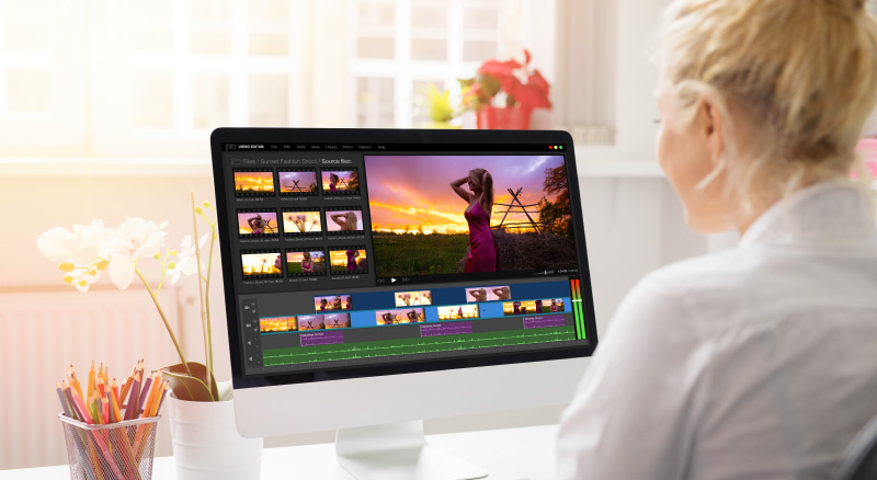 A person editing photos on a computer with sunset images displayed on the screen