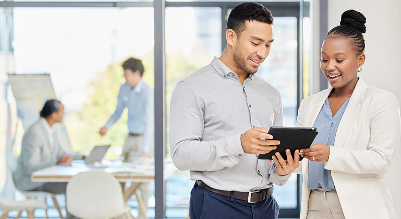 Two co-workers review a digital tablet together