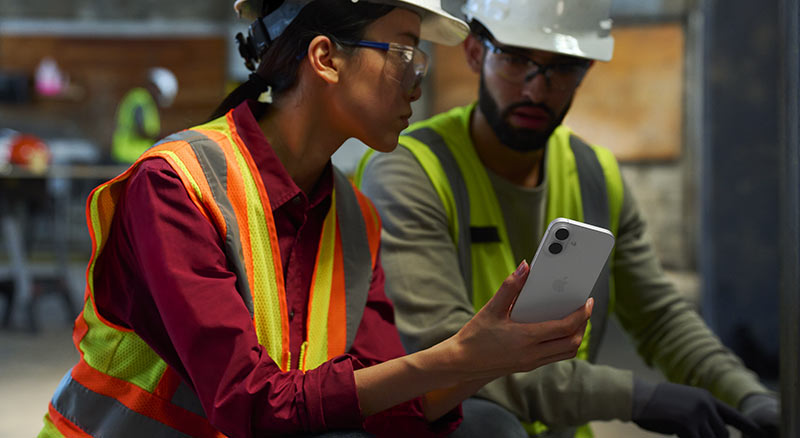 A person holding a tablet stands in an aisle between tall shelves in a warehouse