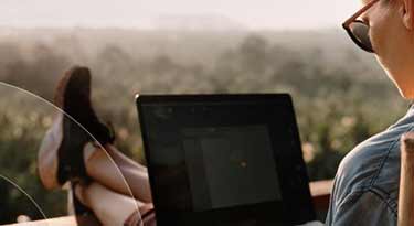 Woman working on her device outside with her feet up on the deck railing