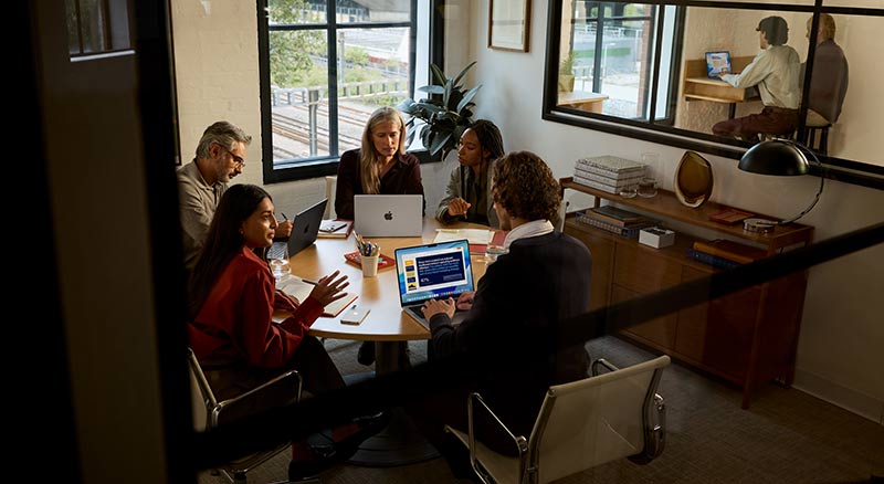 A smiling consultant listens while writing in a notebook