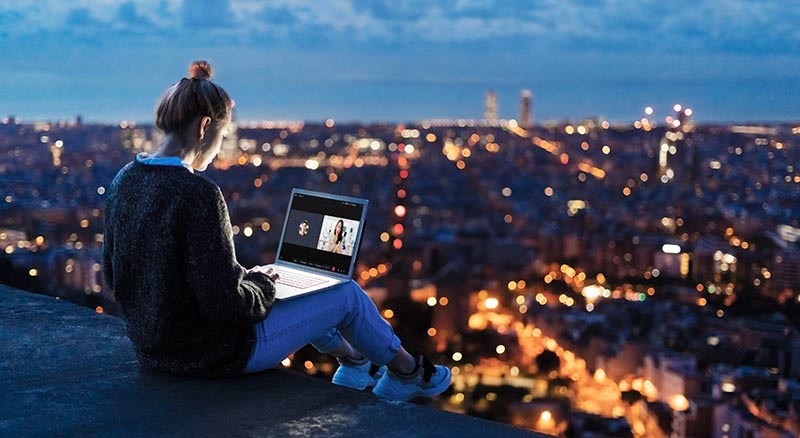 An employee working remotely outside overlooking city