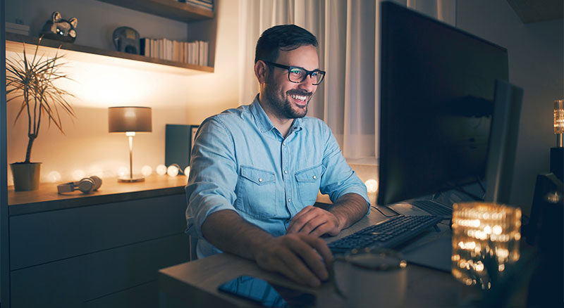 A person sitting at a dimly lit desk with a computer monitor and keyboard