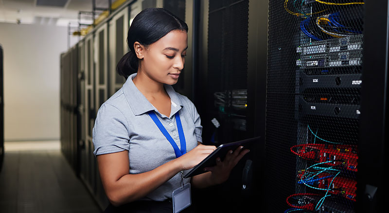 A person standing in front of a server rack with a tablet in hand