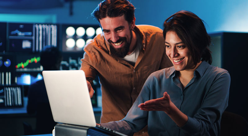 Two people analyze information on a laptop screen