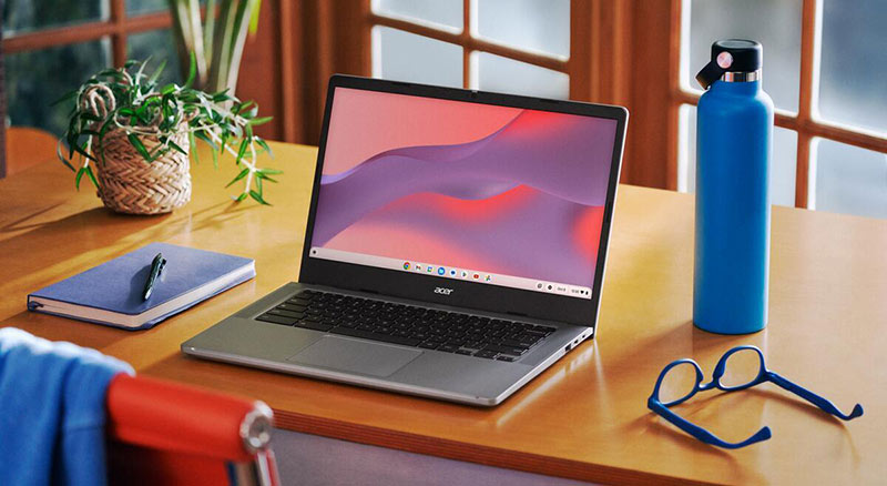 lifestyle shot of chromebook plus on desk next to blue water bottle blue glasses and blue notebook