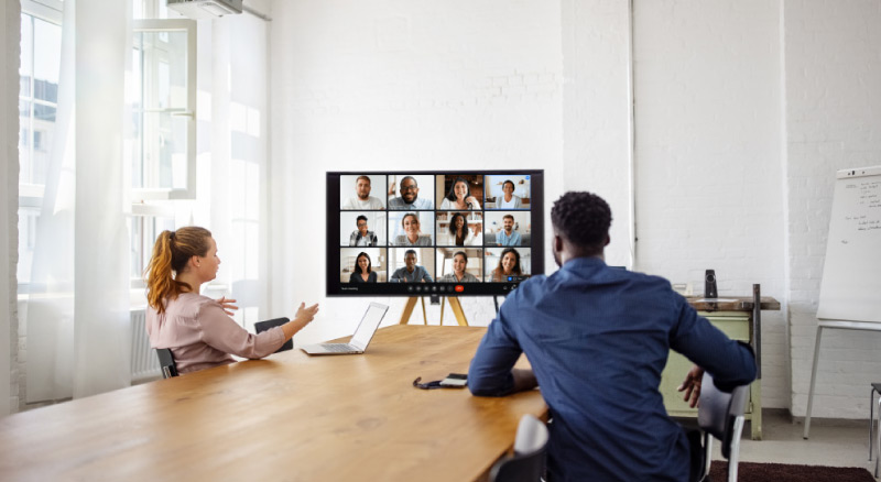 Man and woman in a meeting room on a zoom call