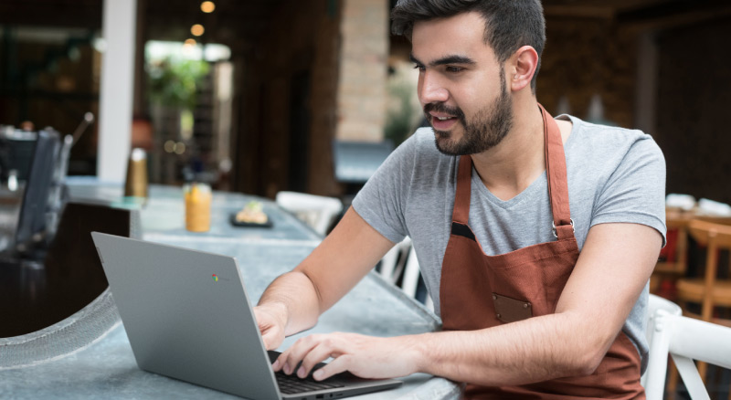 A person in an apron sitting at a table working