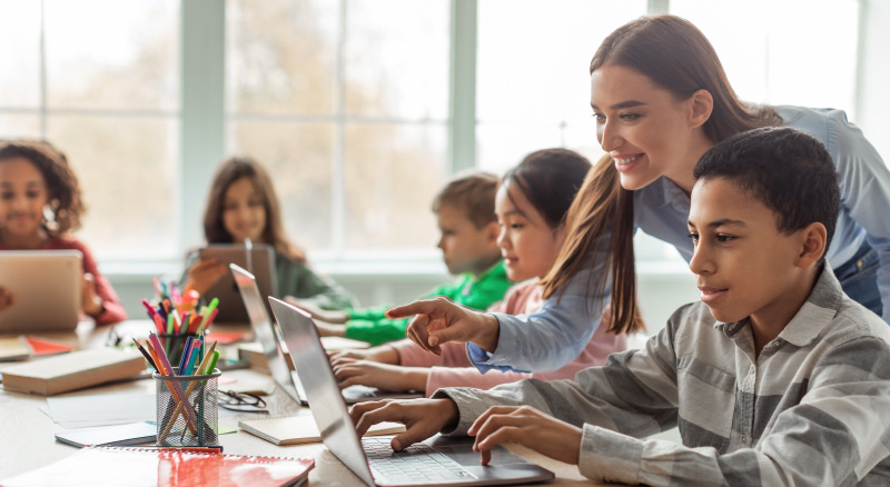 Teacher working with students on laptops