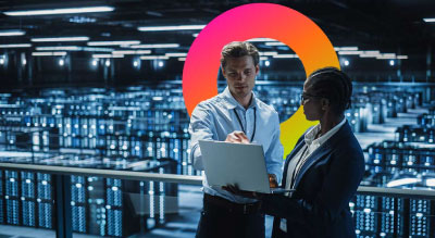 Two people in a server room one on a laptop