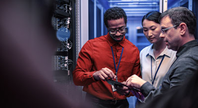 Three professionals examining a server in a data center
