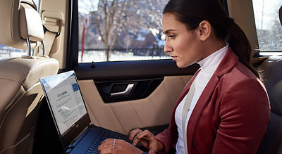 Woman works on laptop in the backseat of a car