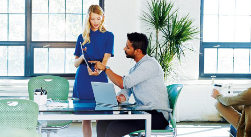 Office setting with two people working on a tablet