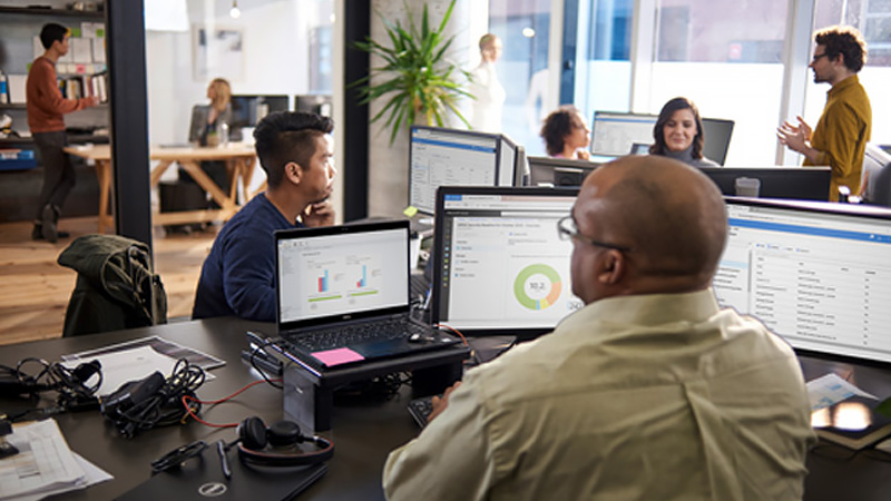 Busy office of employees using multiple computers