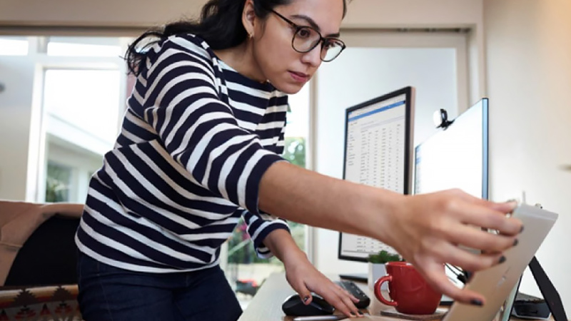 Woman adjusts the angle of her laptop