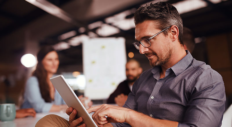 A man sitting in a meeting room with a tablet in his hands