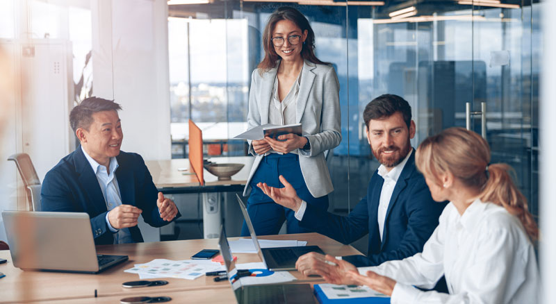 Four employees gather around a table in a meeting