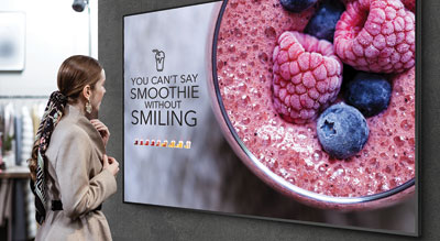 A person looks at a large digital display advertisement featuring a smoothie bowl with berries