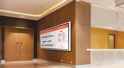 A digital display board in a modern hallway shows informational data in a public setting