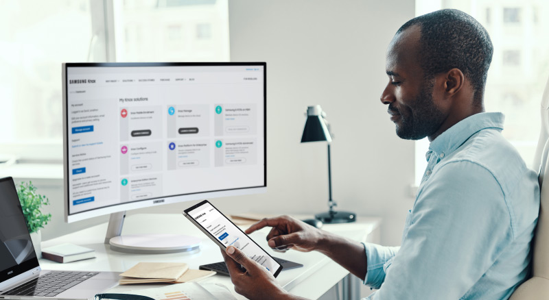 Man working on tablet in front of computer monitor