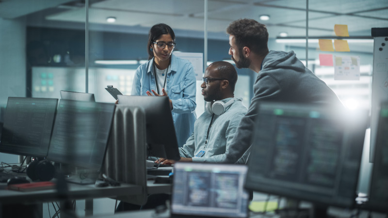 Three people working together on desktop computer