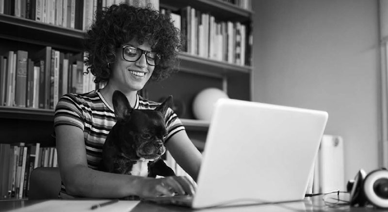 Woman with dog on her lap typing on the computer