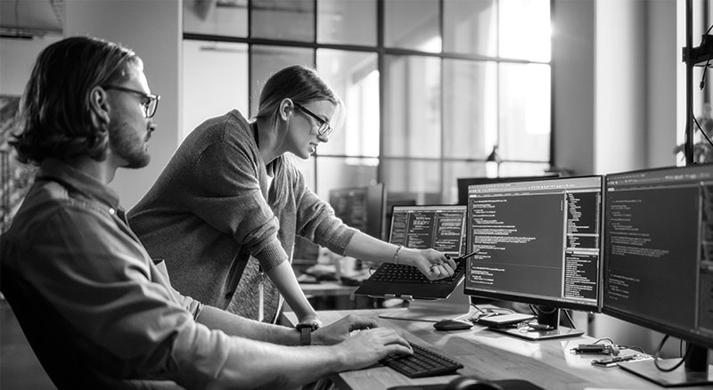 Co-workers analyzing code on a computer