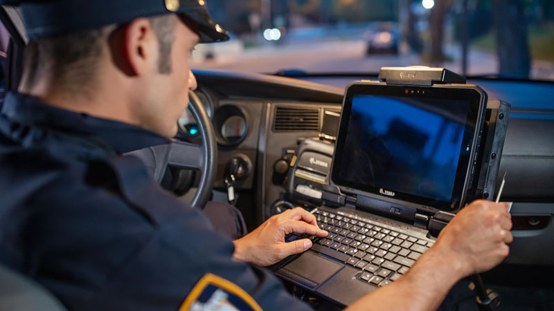Police officer uses mobile tablet in his car