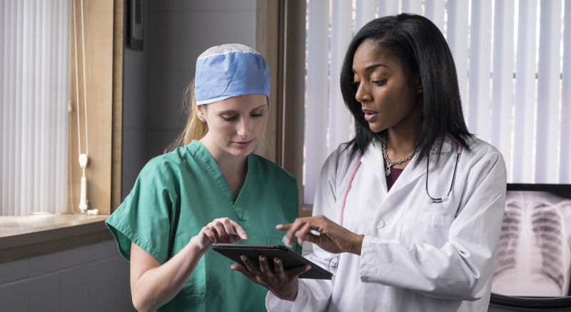 Woman doctor and nurse on ipad