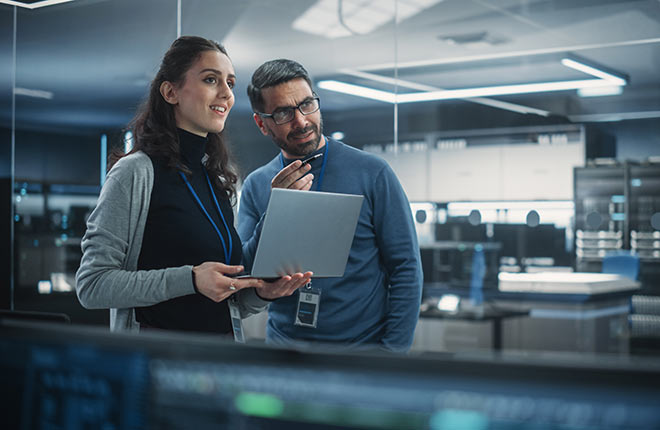 two individuals with a laptop in a data center working