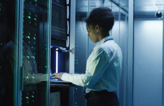 An individual working on. a laptop in a data storage server